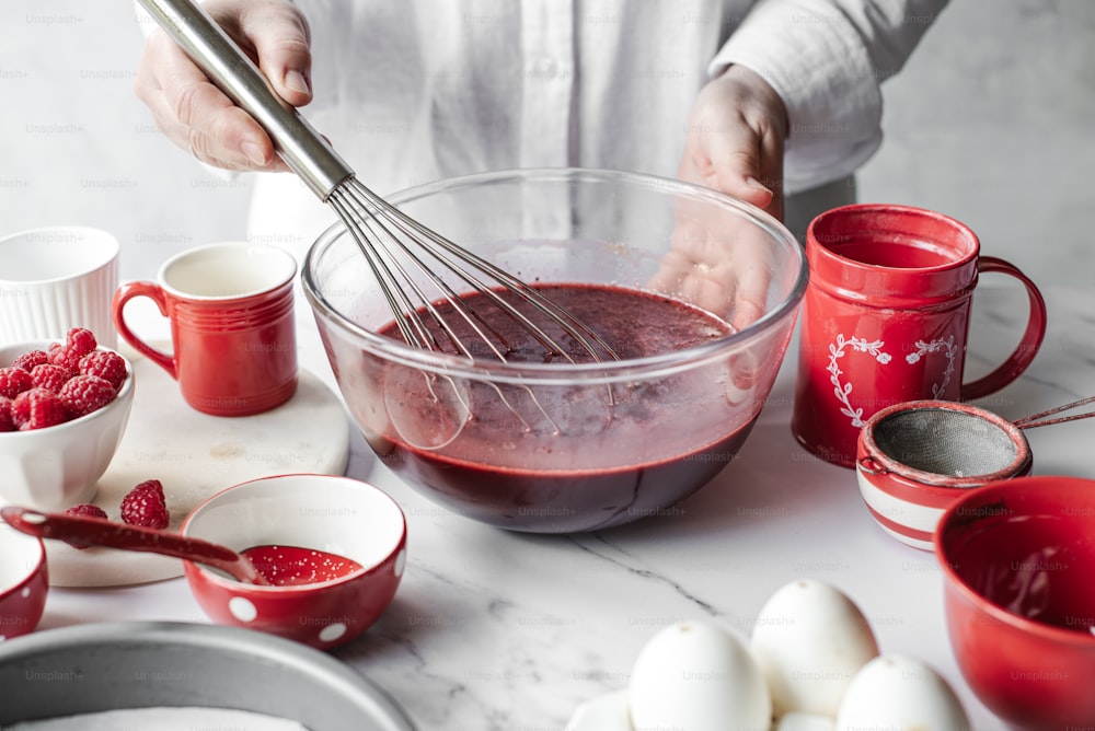 a person whisking raspberries in a bowl