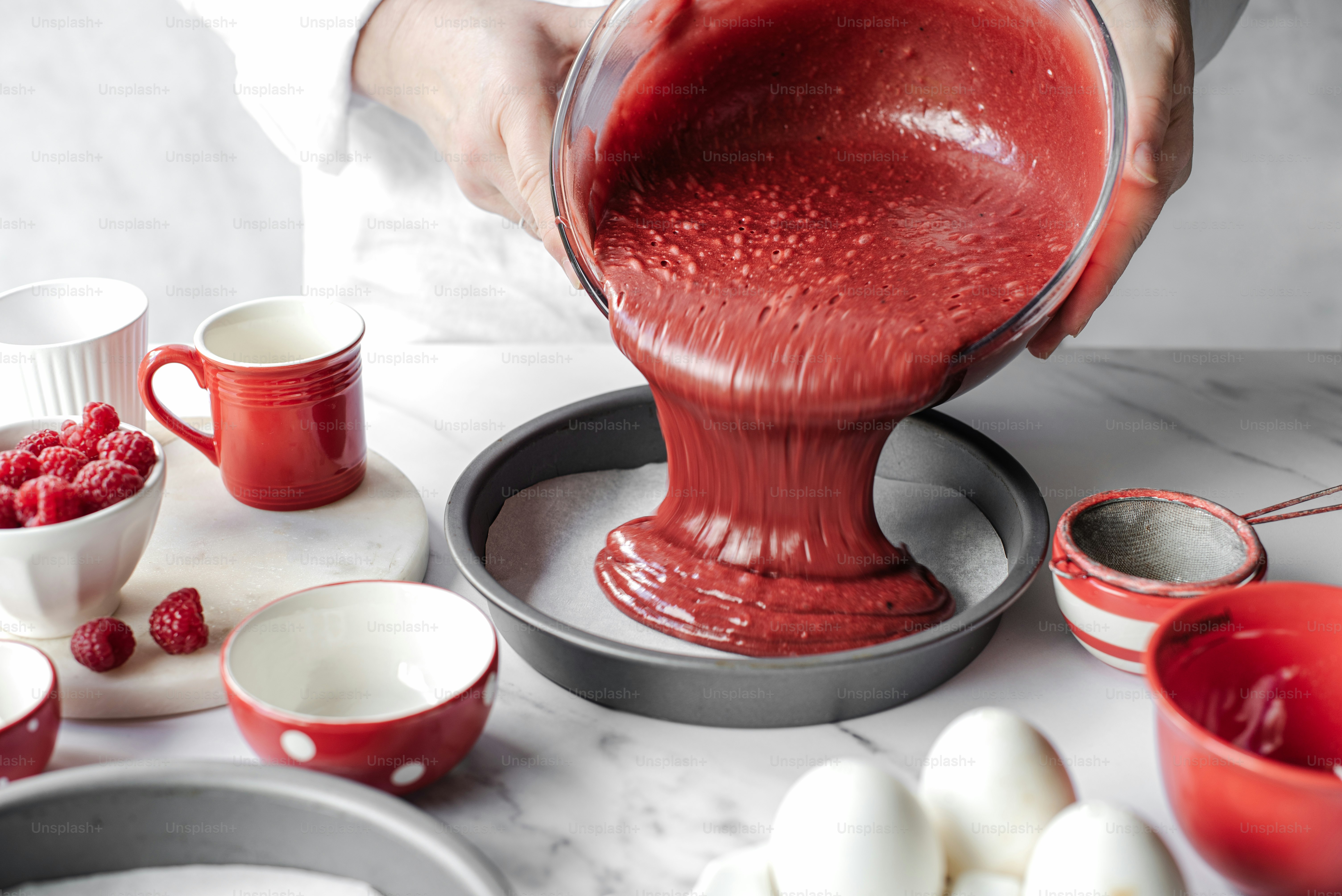 a person pouring red liquid into a pan