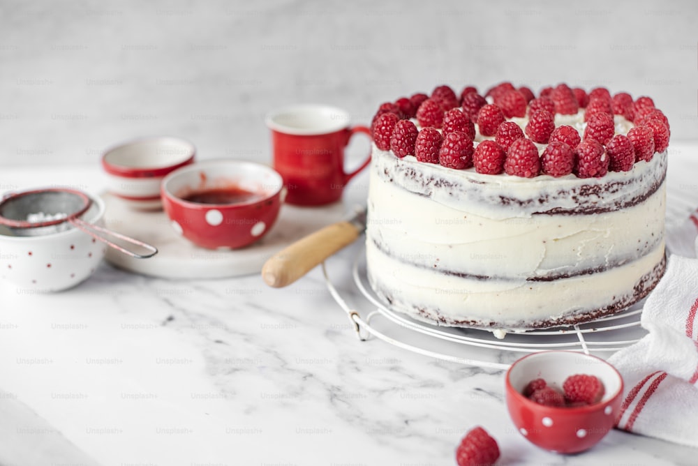 un gâteau avec un glaçage blanc et des framboises sur le dessus