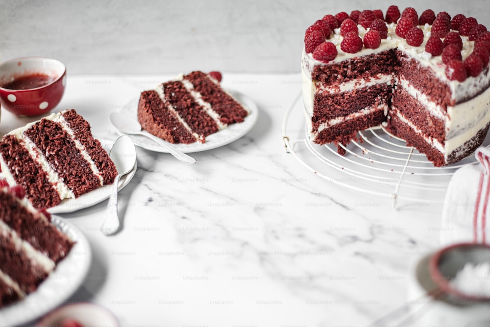 ein Stück Red Velvet Cake mit weißem Zuckerguss und Himbeeren