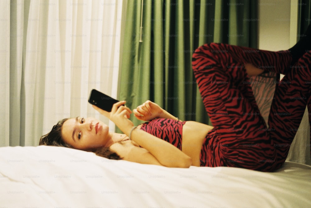 a woman laying on a bed holding a remote control