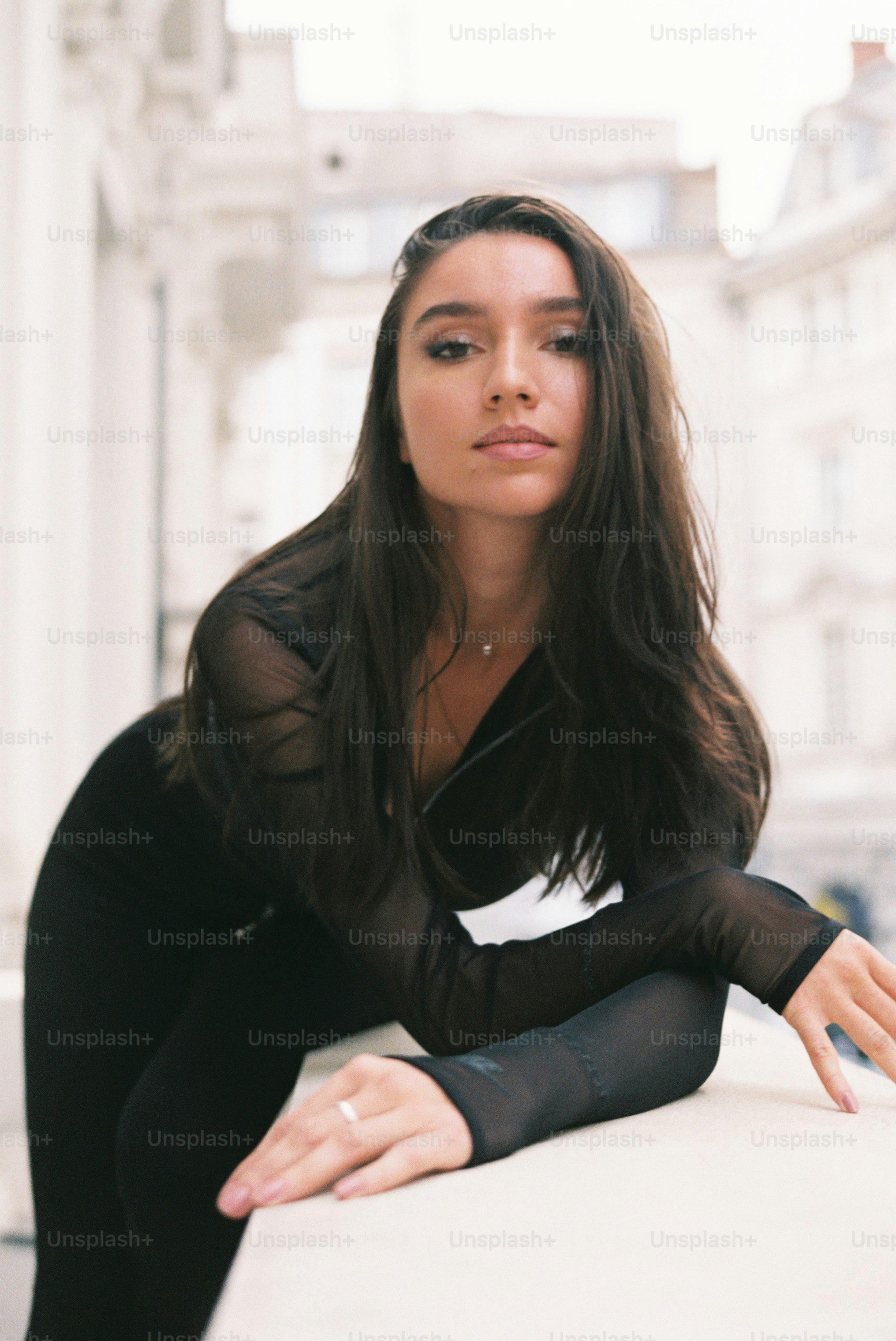 a woman sitting on a ledge in a black outfit