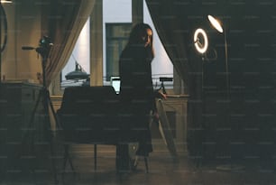 una mujer de pie en una habitación oscura junto a una ventana