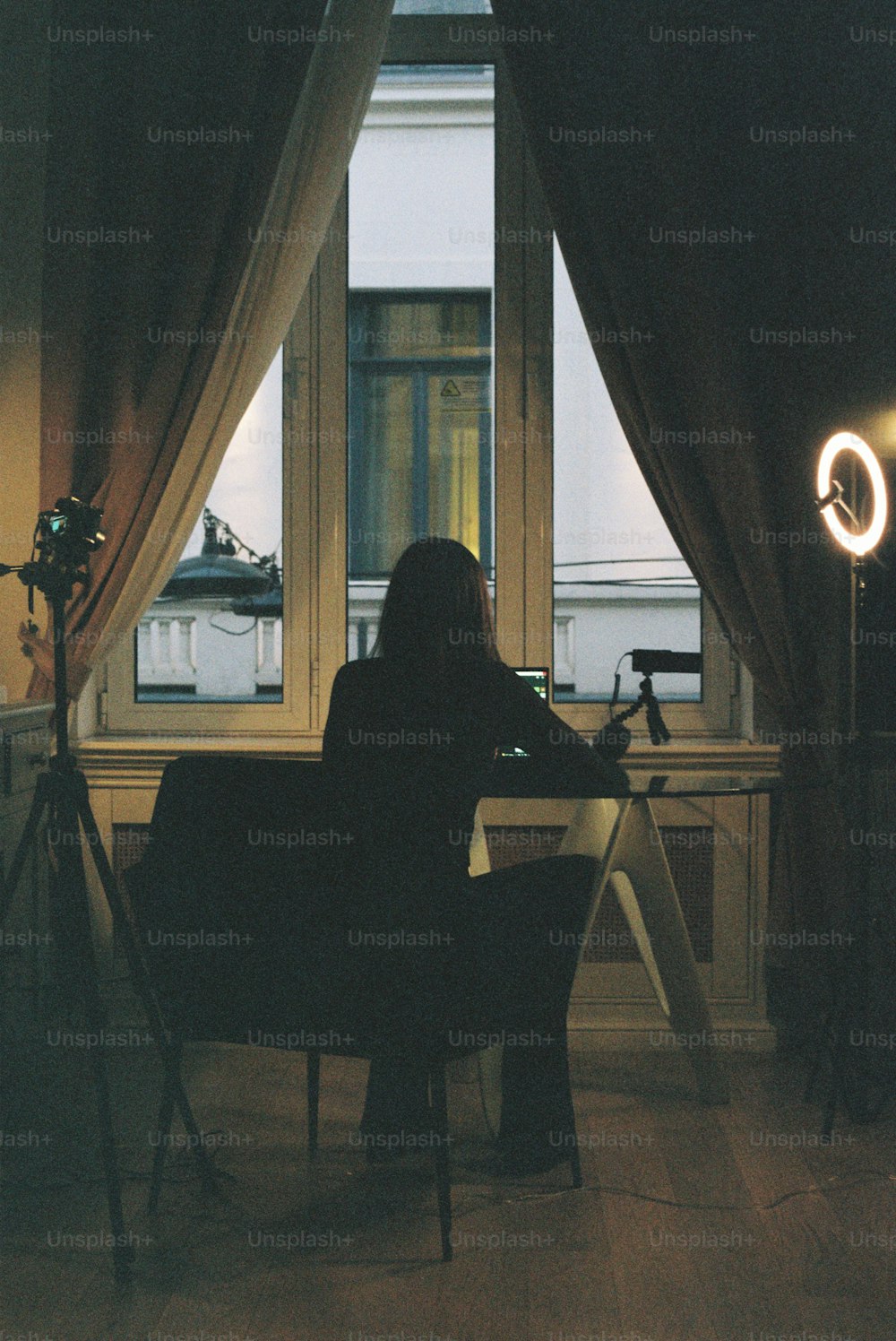 a woman sitting at a desk in front of a window