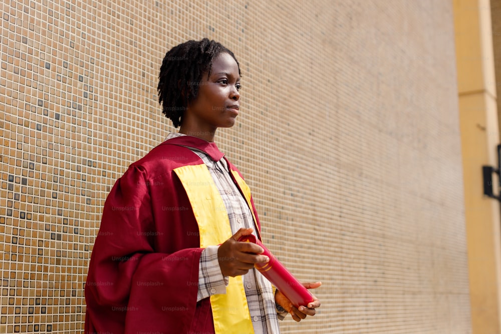 a woman in a graduation gown standing in front of a wall