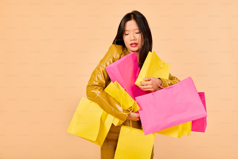a woman in a yellow jacket holding pink and yellow shopping bags