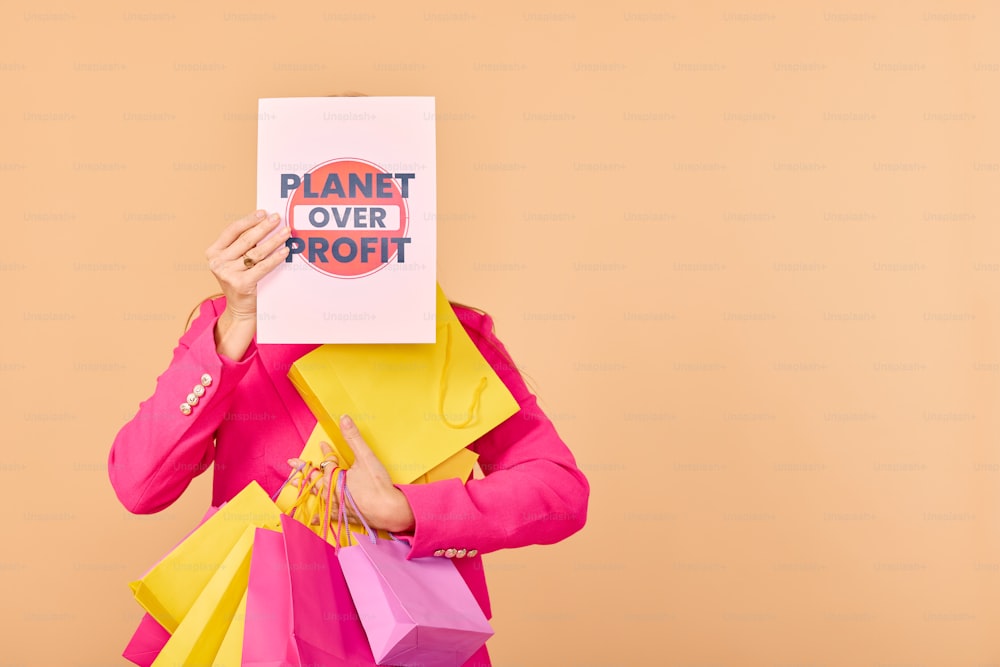 a woman holding a sign that says planet over profits