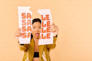 Una mujer sosteniendo dos hojas de papel con las palabras "Sale"