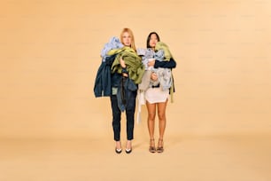 Dos mujeres de pie una al lado de la otra sosteniendo ropa