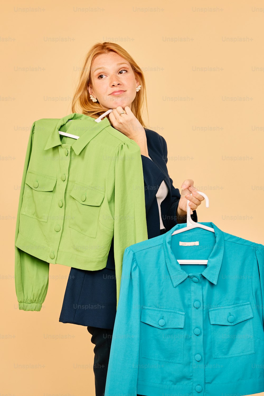 a woman holding a green jacket and a blue jacket
