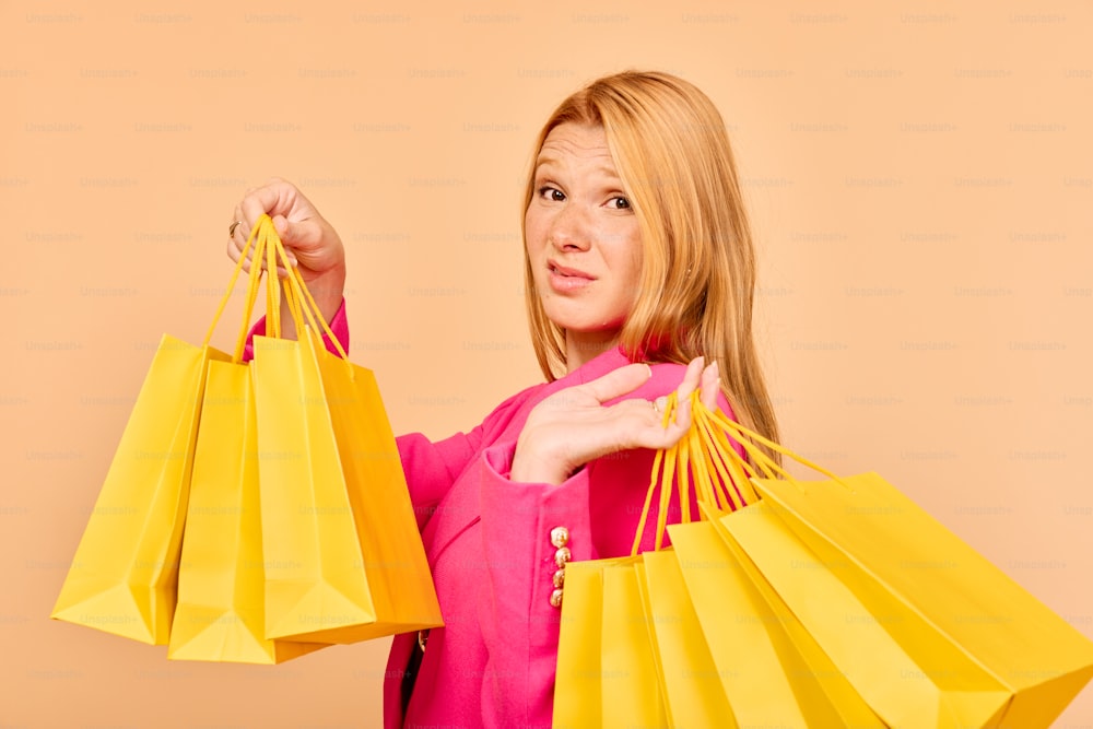 a woman in a pink shirt holding yellow shopping bags