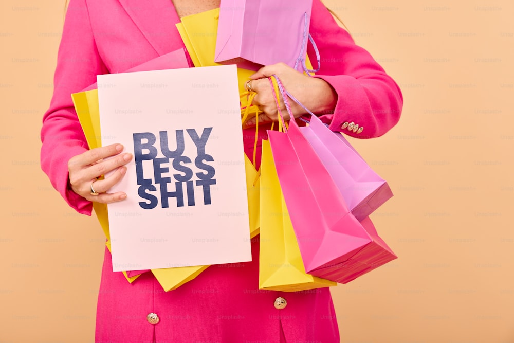 una mujer con un cartel que dice "compre menos mierda"
