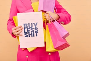 a woman holding a sign that says buy less shit