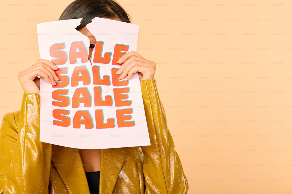 a woman covering her face with a sale sign