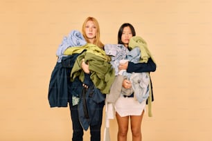 due donne in piedi l'una accanto all'altra che tengono i vestiti