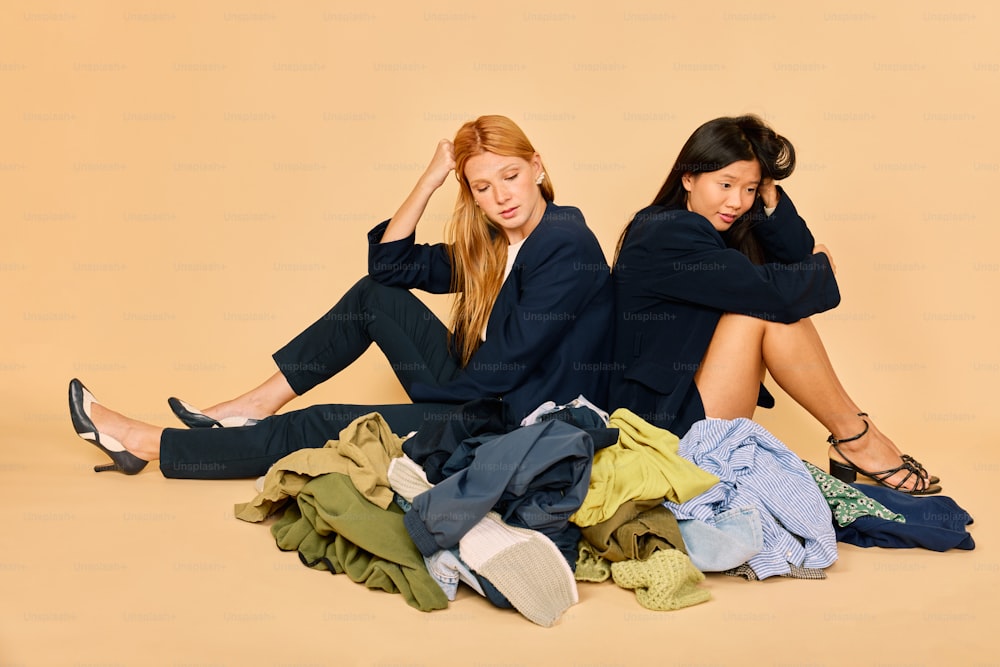 two women sitting on the ground with clothes