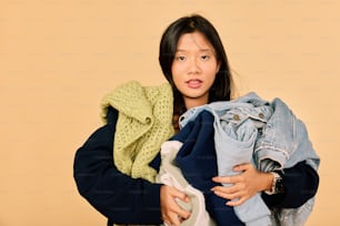 a woman is holding a pile of clothes