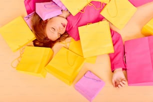 a woman laying on the ground surrounded by shopping bags