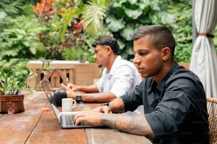 two men sitting at a table with a laptop