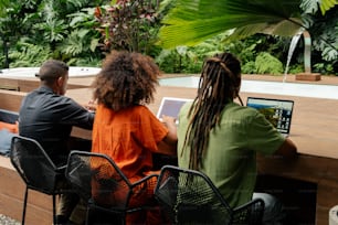 three people sitting at a table with a laptop