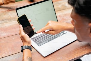 a person sitting at a table with a laptop and a cell phone