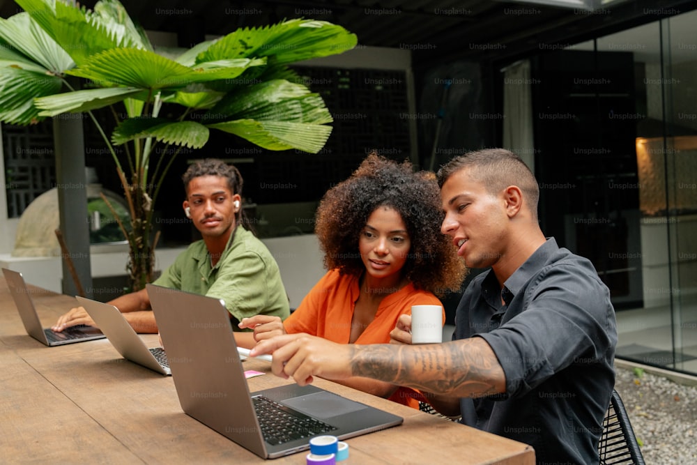 a group of people sitting at a table with laptops