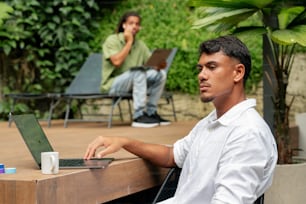 a man sitting at a table using a laptop computer