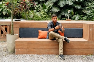 a man sitting on a wooden bench holding a cell phone