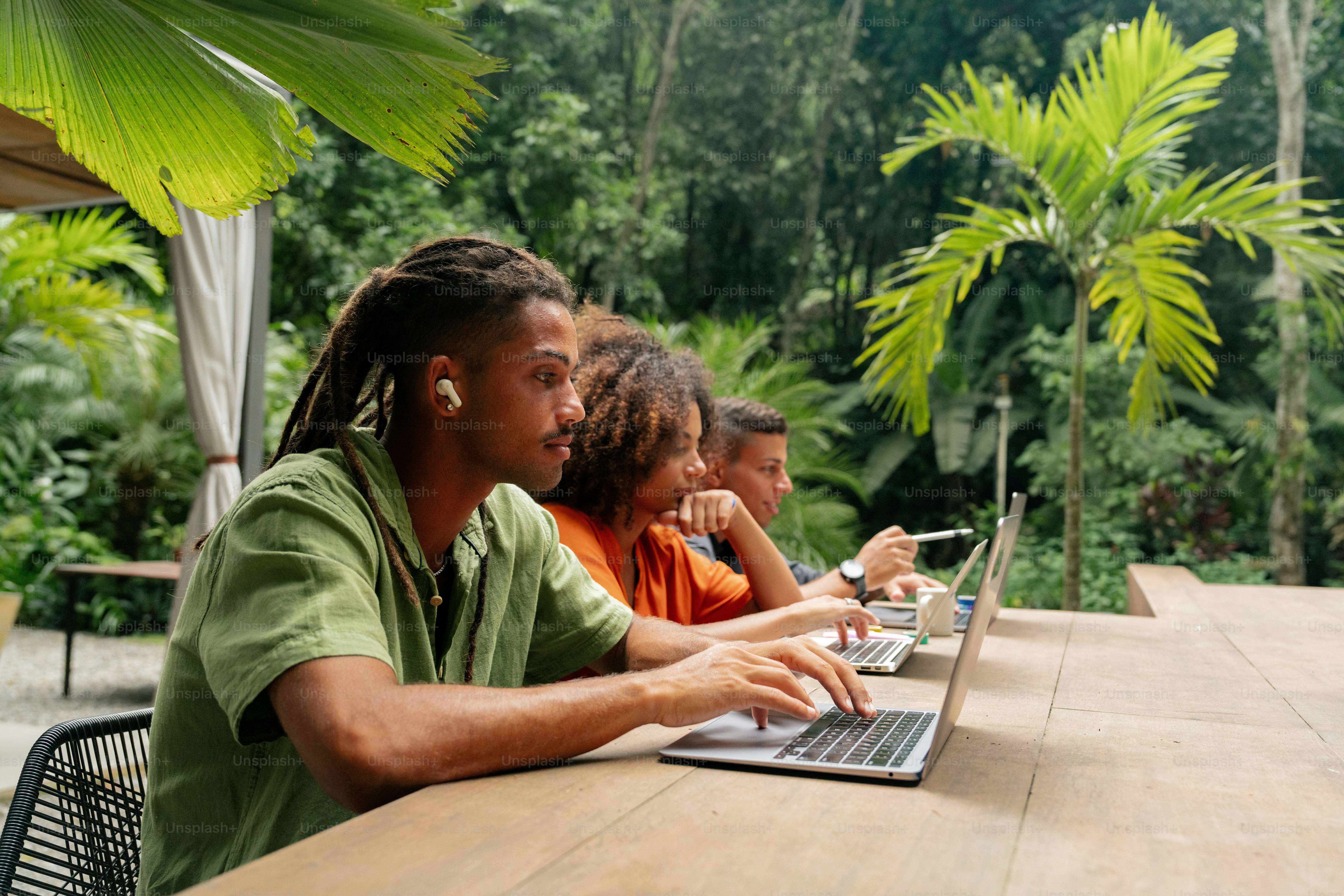 a group of people sitting at a table with laptops