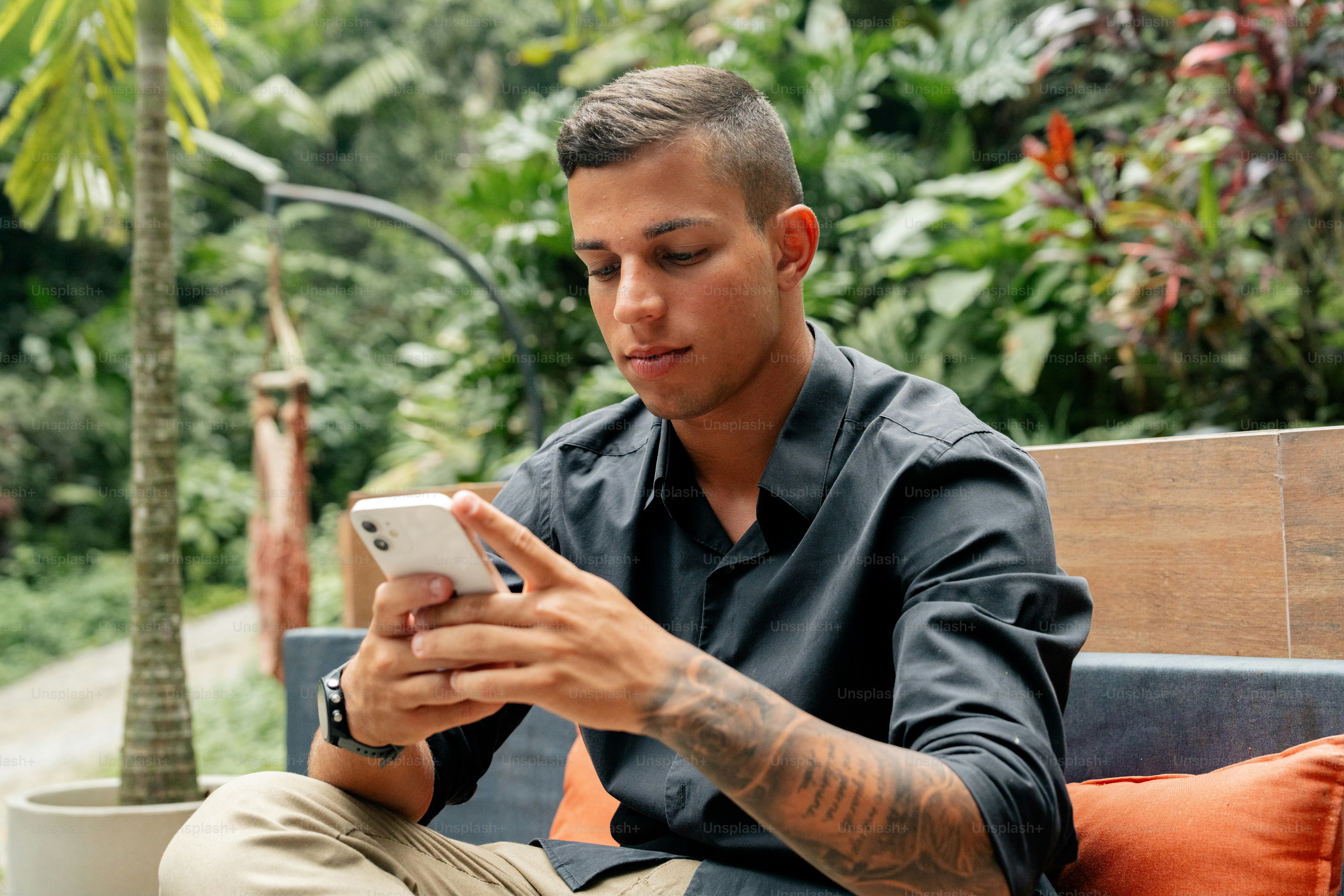 ベンチに座って携帯電話を見ている男性