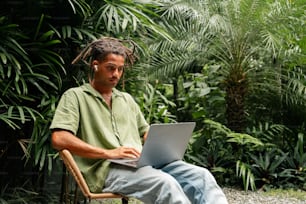 ein Mann, der auf einem Stuhl sitzt und einen Laptop benutzt
