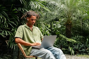 a man sitting in a chair using a laptop computer