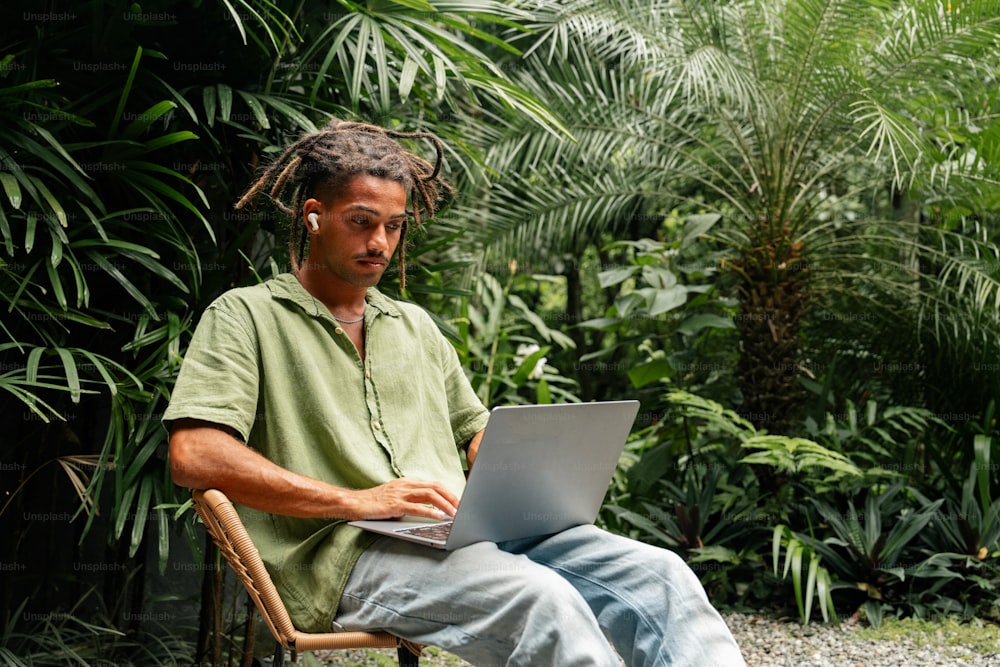 Un hombre sentado en una silla usando una computadora portátil