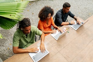 tre persone sedute a un tavolo con computer portatili