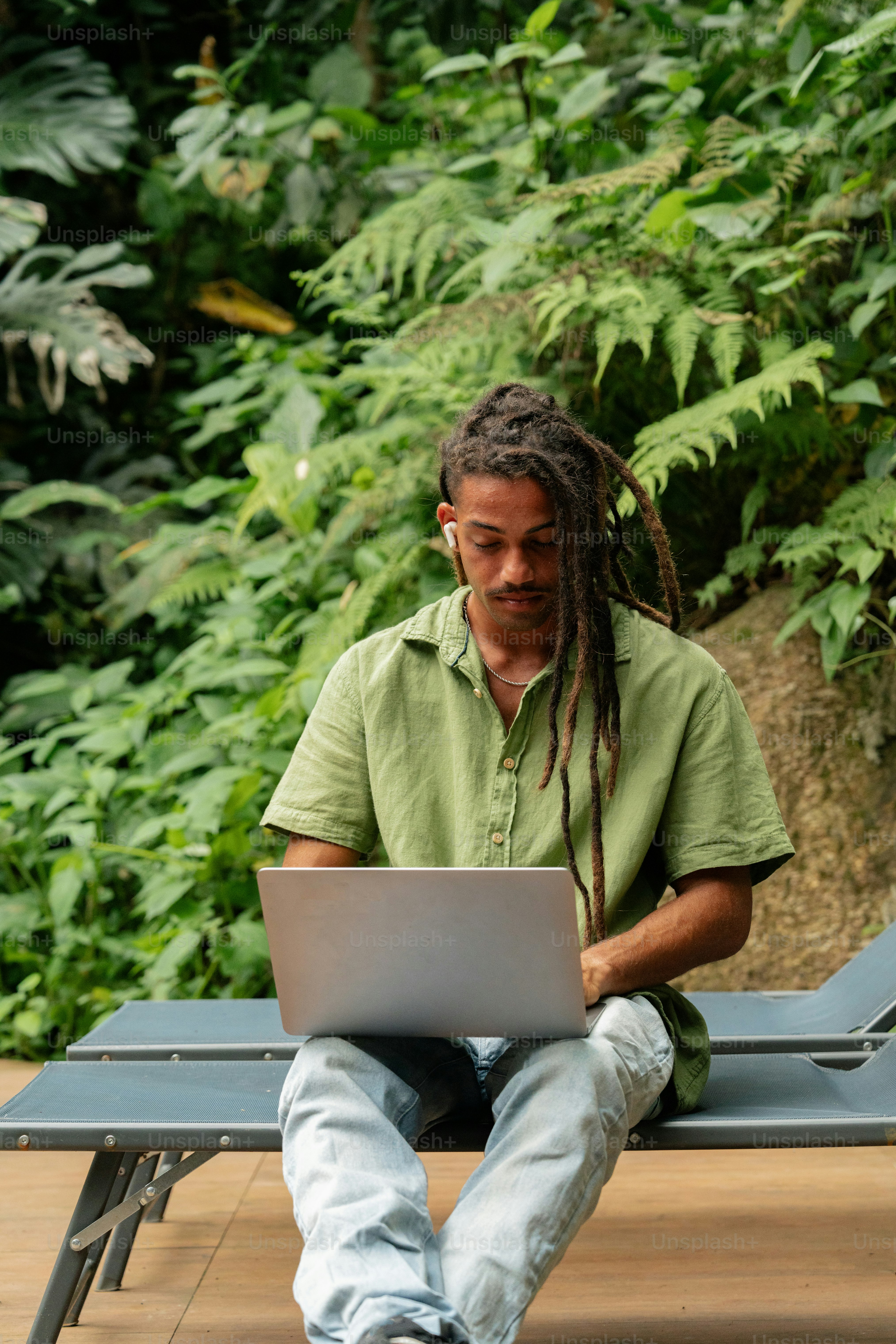 a man sitting on a bench using a laptop computer