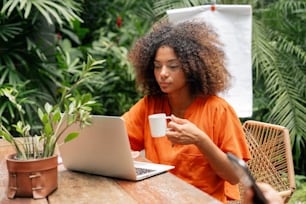 a woman sitting at a table using a laptop computer