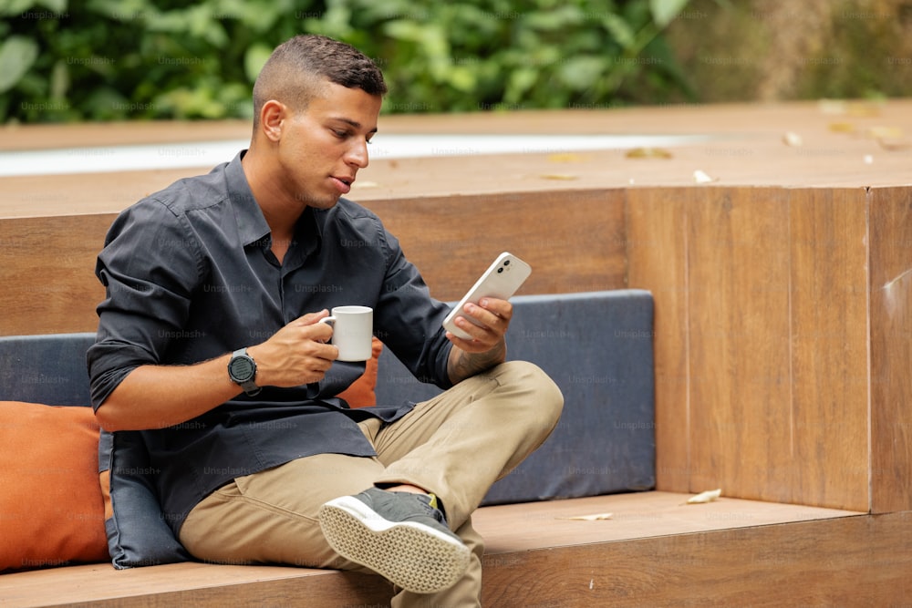 Un hombre sentado en un banco usando un teléfono celular
