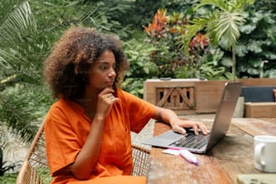 a woman sitting at a table using a laptop computer