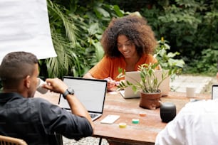 a group of people sitting around a table with laptops