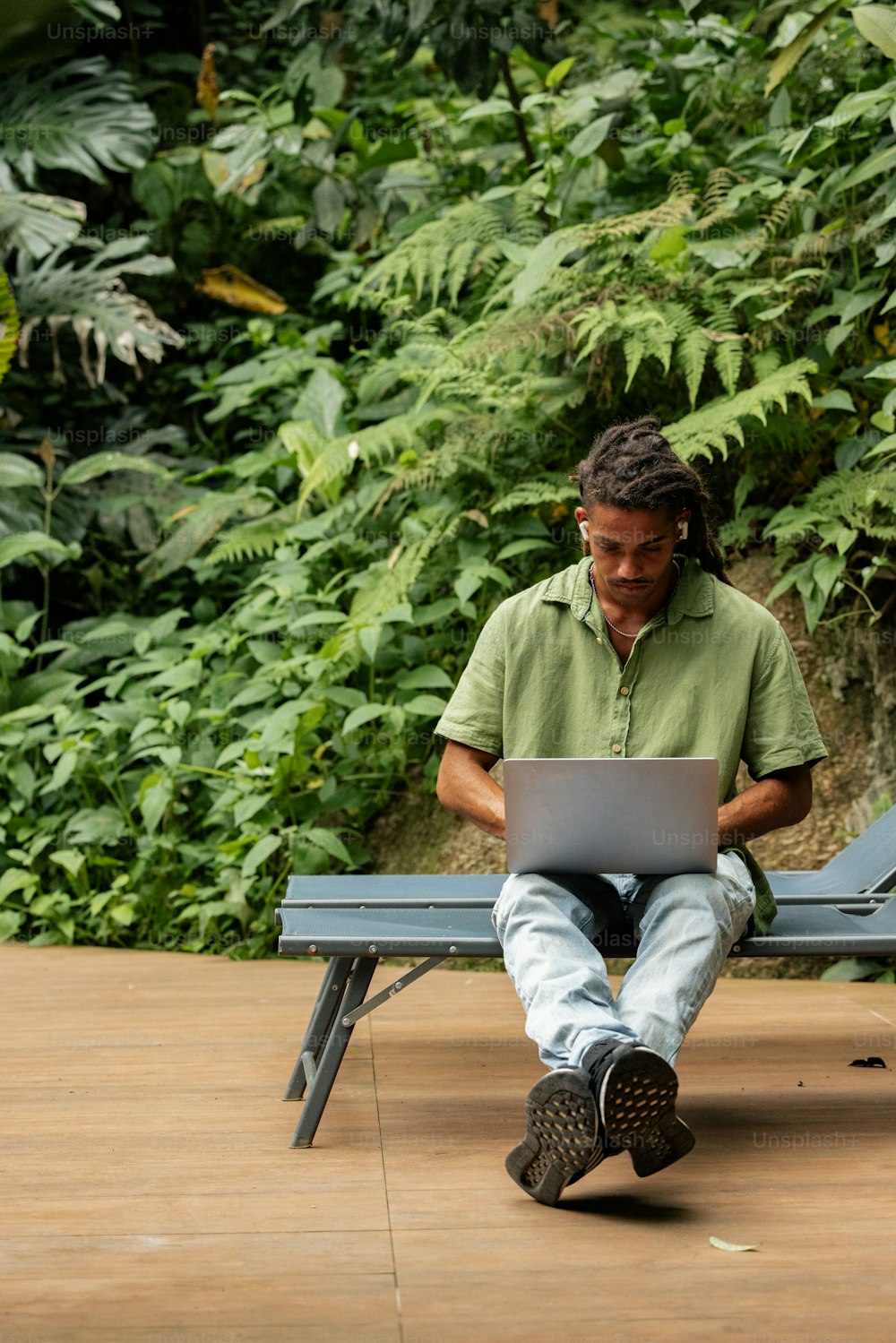 a man sitting on a bench using a laptop computer