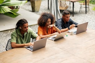 a group of people sitting at a table with laptops