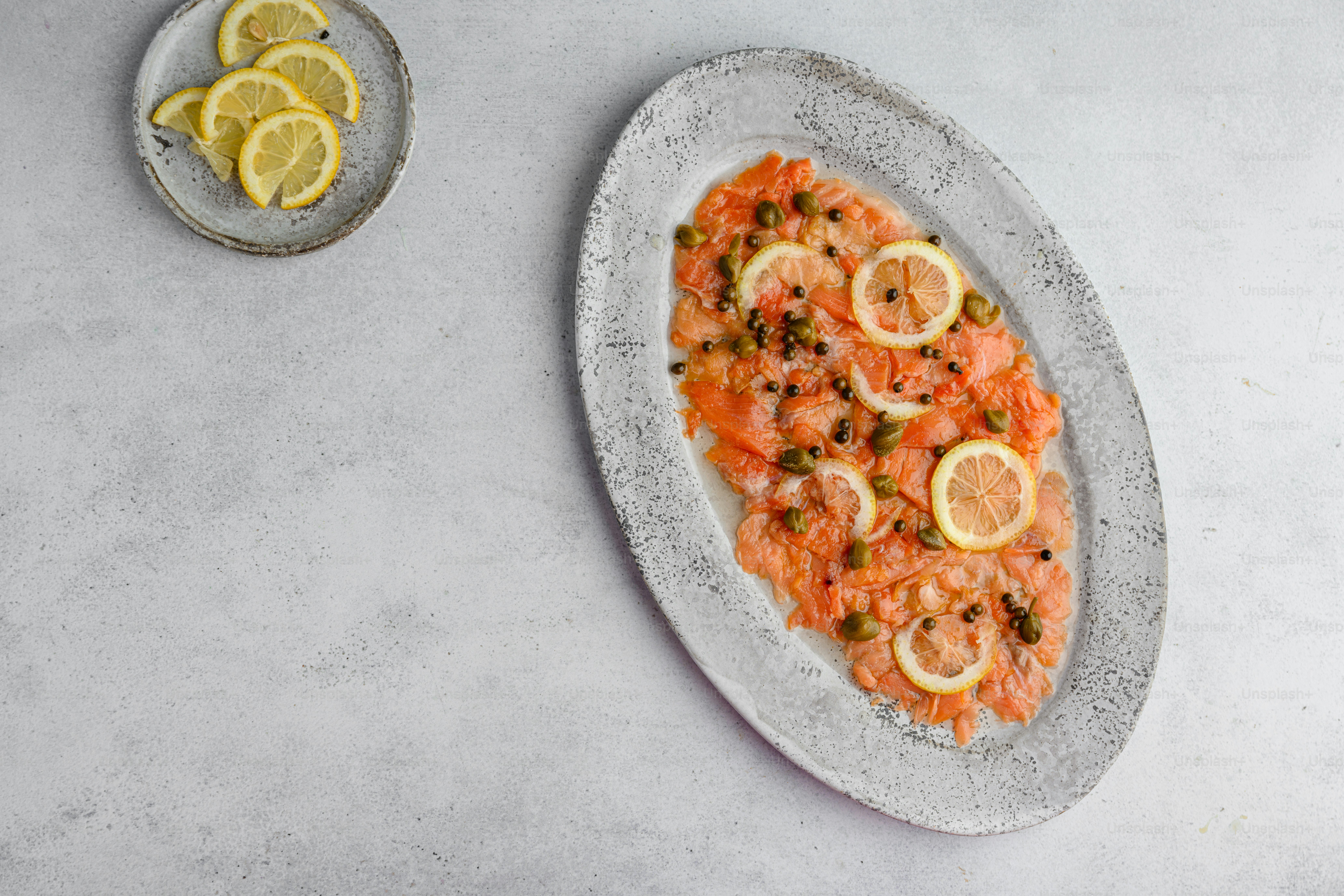 a plate of salmon with lemons and capers
