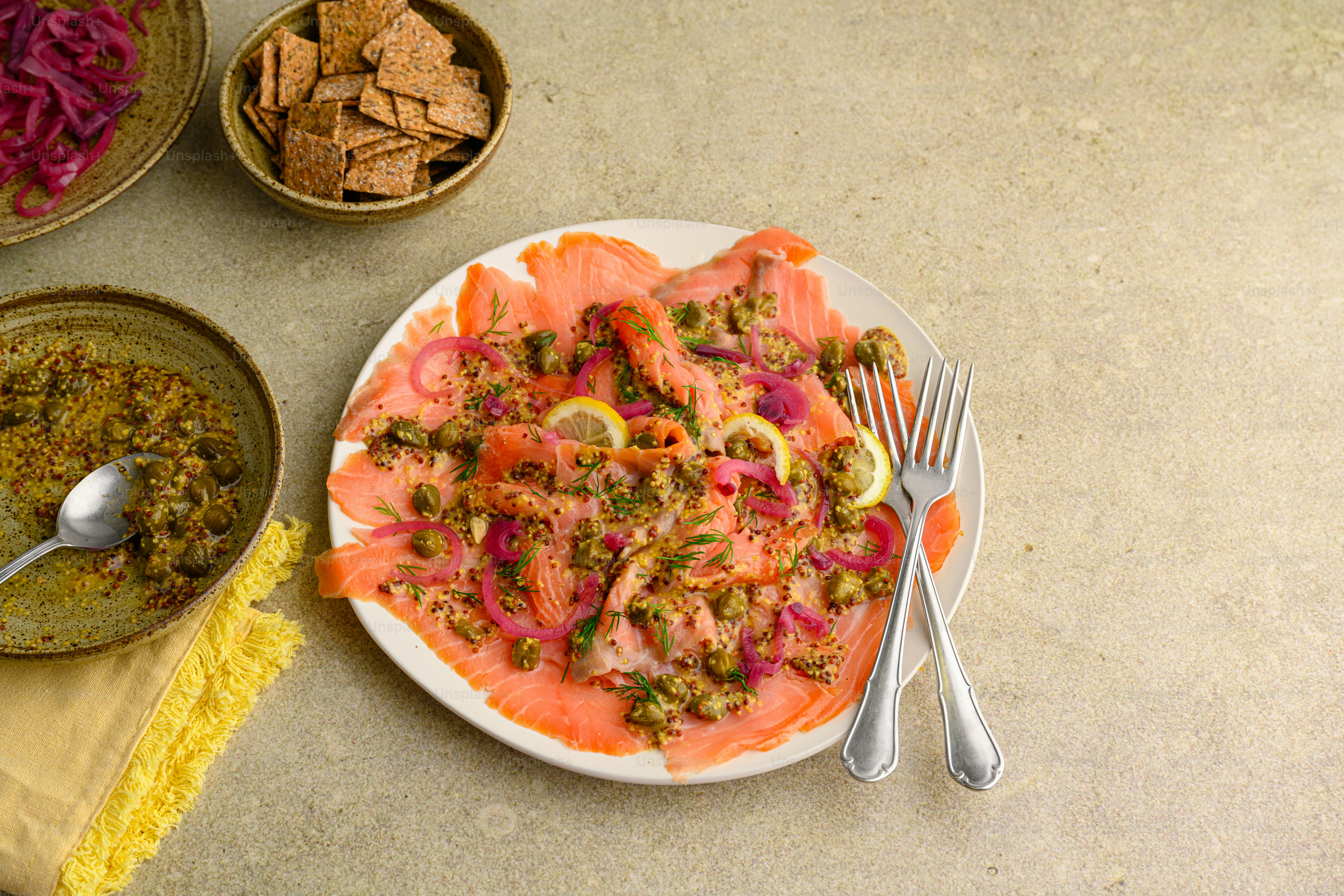 ein weißer Teller mit Fisch neben Schüsseln mit Essen