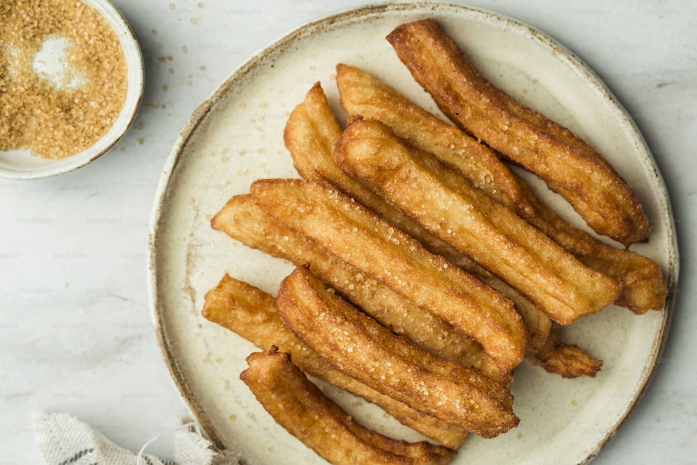 a white plate topped with french fries next to a bowl of seasoning