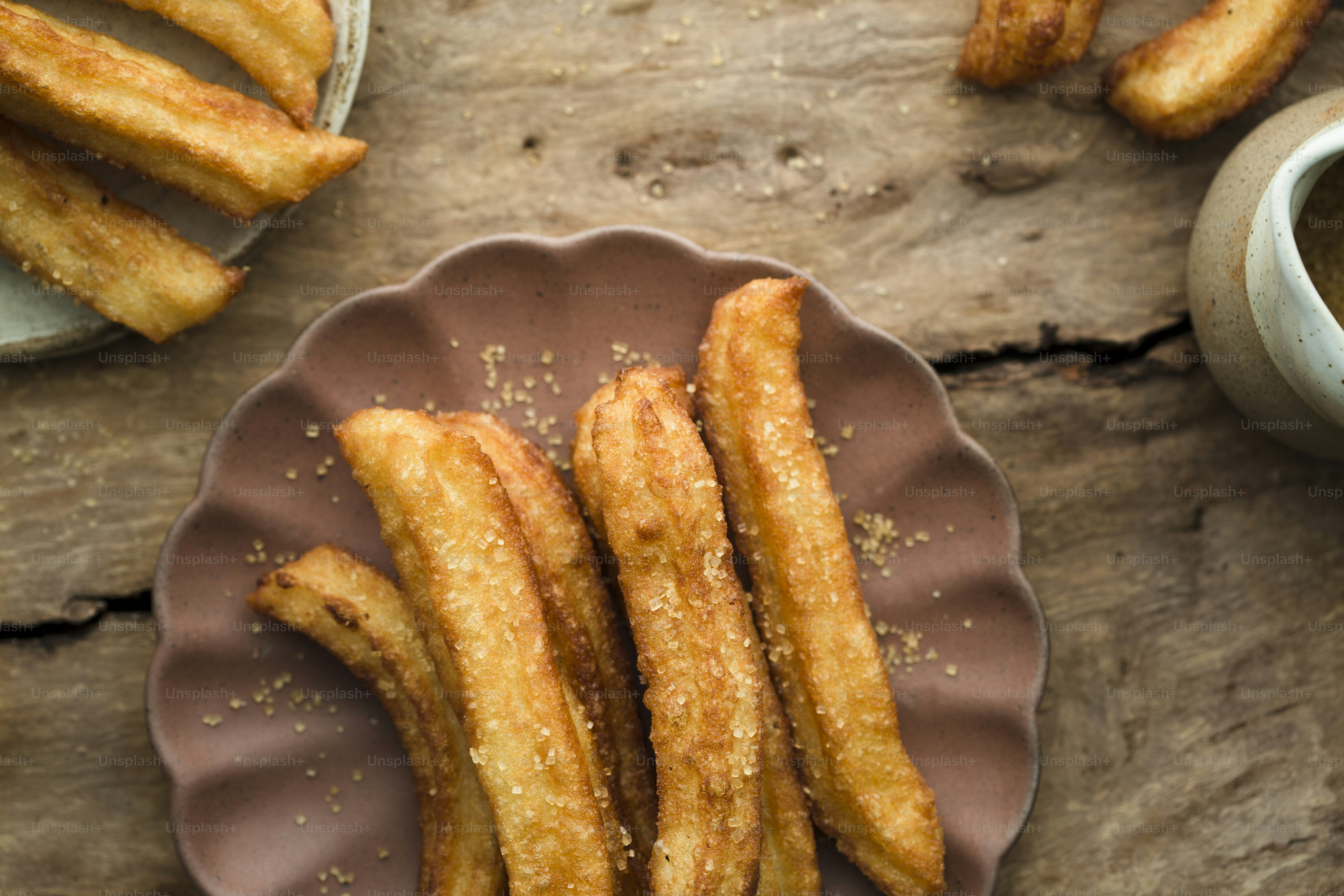 a plate of churros next to a cup of coffee