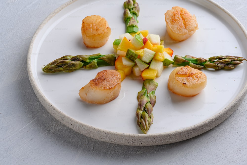 a white plate topped with scallops and vegetables
