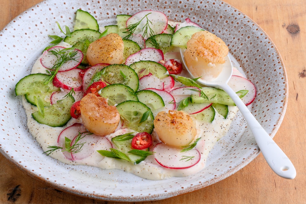 a bowl of food with cucumbers, radishes, and other vegetables