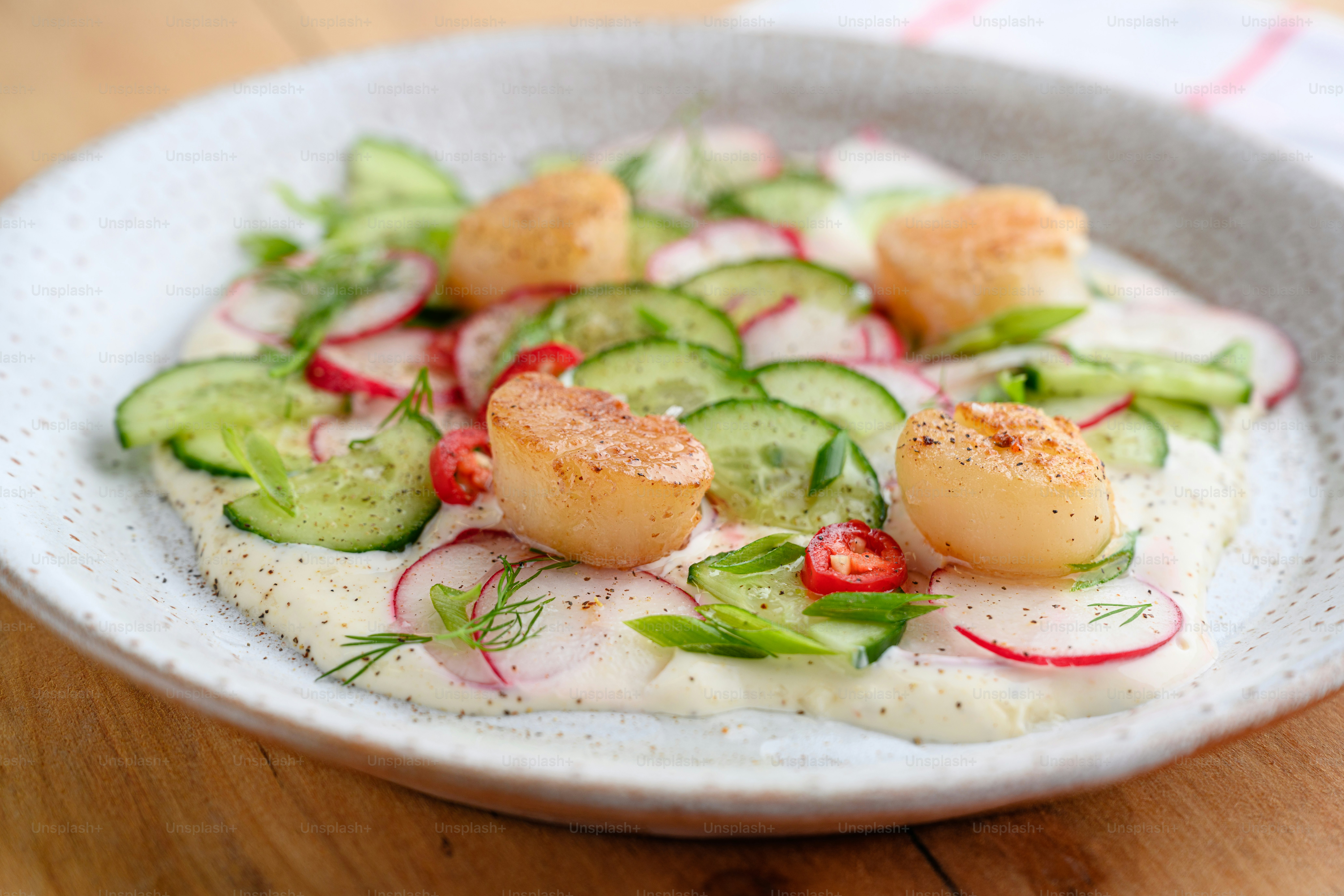 une assiette blanche garnie de concombres et de sauce