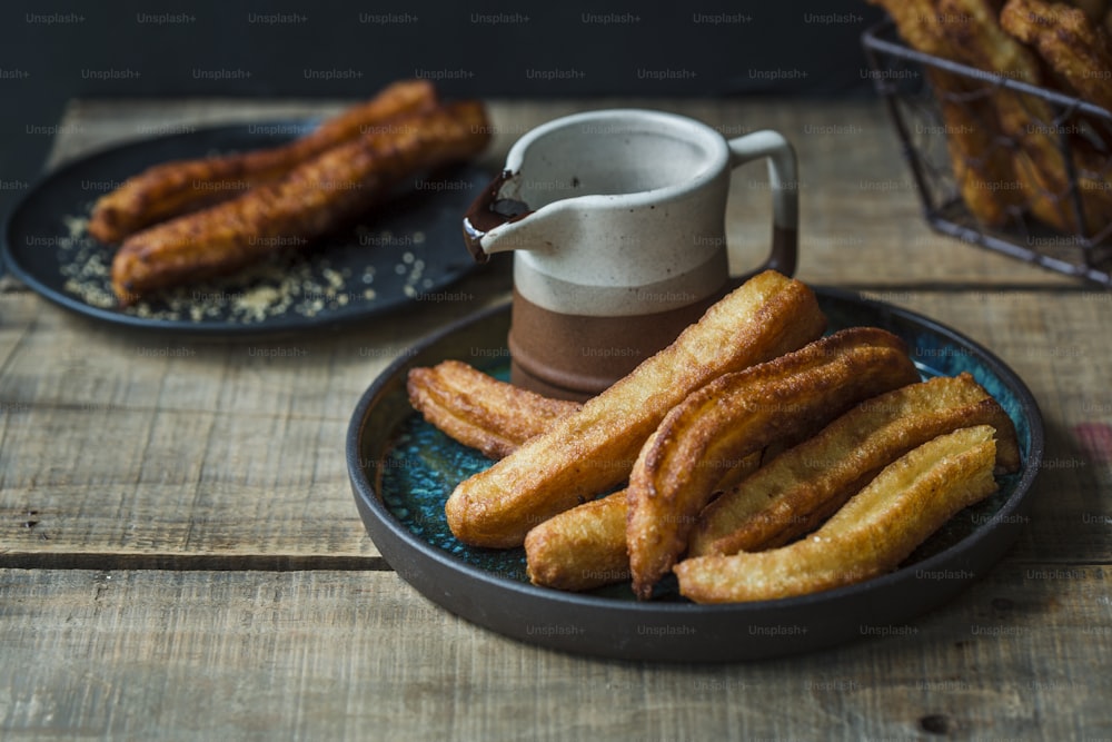 a plate of churros next to a cup of coffee