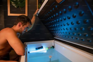 a shirtless man is looking into an open refrigerator